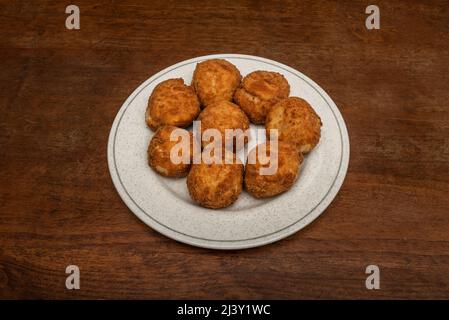 Köstliche runde Kroketten mit frischem Käse und Schinkentacos auf einem runden Teller Stockfoto