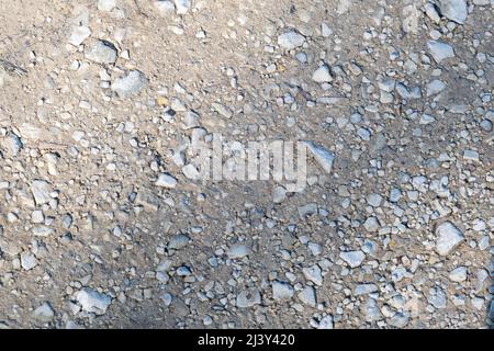 Steinige Wüstenbodenstruktur. Grauer trockener Boden mit kleinen Steinen. Nahaufnahme von oben. Stockfoto