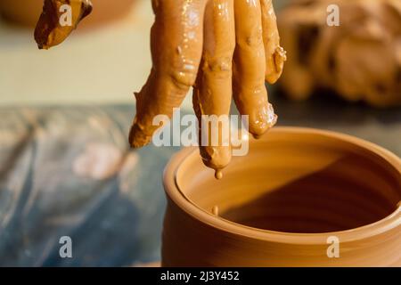 Töpferhände, die einen Tonkrug aus der Nähe machen. Stockfoto