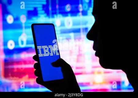 In dieser Abbildung hält eine Frau ein Smartphone mit dem Logo der International Business Machines Corporation (IBM) auf dem Bildschirm. Stockfoto