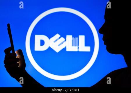 In dieser Fotobilder hält die Silhouette einer Frau ein Smartphone mit dem Dell-Logo im Hintergrund. Stockfoto