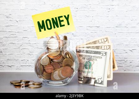 Dollar und Münzen in Glas jar mit Spenden Label, Finanzkonzept. Vintage-Ton aus Holz Hintergrund mit dramatischen Licht. Stockfoto