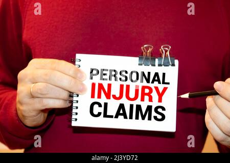 Geschäftsmann mit Notizbuch mit Text Personenschäden-Schadenfälle Stockfoto