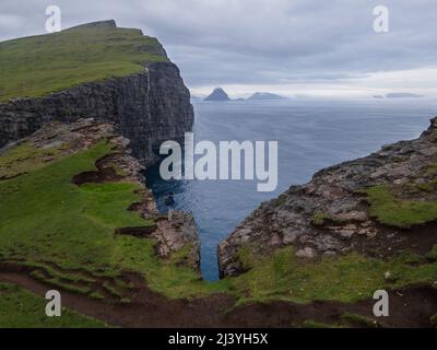 Wunderschöne filmische Luftaufnahme des Wasserfalls von Bøsdalafossur und des Sees von Trælanípan - Lagune herrliche Wahrzeichen auf den Färöer Inseln Stockfoto