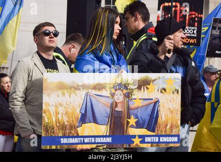 London, Großbritannien. 10.. April 2022. Eine Frau, deren Haare mit den Farben der ukrainischen Flagge gefärbt sind, hält ein Schild. Demonstranten versammelten sich vor der Downing Street in Solidarität mit der Ukraine, als Berichte über Massaker in Bucha und anderen Städten in der Ukraine und über Gräueltaten, die angeblich von russischen Truppen begangen wurden, auftauchten. Kredit: Vuk Valcic/Alamy Live Nachrichten Stockfoto