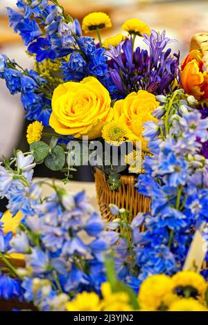 Gelbe und blaue Blumenarrangements zum Verkauf bei einer Wohltätigkeitsveranstaltung, um Geld für ukrainische humanitäre Hilfe zu sammeln Stockfoto