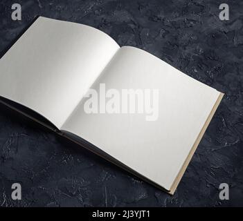 Foto eines leeren geöffneten Notizbuches auf schwarzem Gips-Hintergrund. Vorlage für Portfolios von Grafikdesignern. Stockfoto