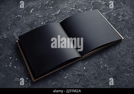 Leere, schwarz geöffnete Broschüre auf schwarzem Gips-Hintergrund. Modell für Portfolios von Grafikdesignern. Stockfoto