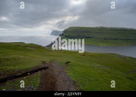 Wunderschöne filmische Luftaufnahme des Wasserfalls von Bøsdalafossur und des Sees von Trælanípan - Lagune herrliche Wahrzeichen auf den Färöer Inseln Stockfoto