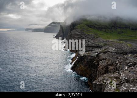 Wunderschöne filmische Luftaufnahme des Wasserfalls von Bøsdalafossur und des Sees von Trælanípan - Lagune herrliche Wahrzeichen auf den Färöer Inseln Stockfoto