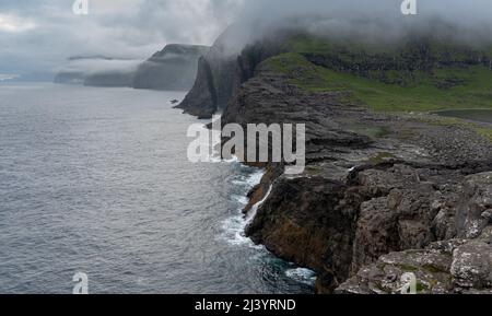 Wunderschöne filmische Luftaufnahme des Wasserfalls von Bøsdalafossur und des Sees von Trælanípan - Lagune herrliche Wahrzeichen auf den Färöer Inseln Stockfoto