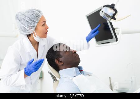 Zahnärztin zeigt auf das Display, um dem Patienten Informationen anzuzeigen Stockfoto