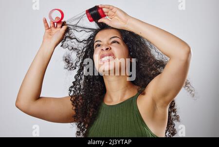 Diese Rollen machen mir immer eine harte Zeit. Aufnahme einer Frau, die runzelte, während sie Rollen aus ihrem Haar zog. Stockfoto