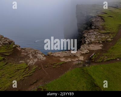 Wunderschöne filmische Luftaufnahme des Wasserfalls von Bøsdalafossur und des Sees von Trælanípan - Lagune herrliche Wahrzeichen auf den Färöer Inseln Stockfoto