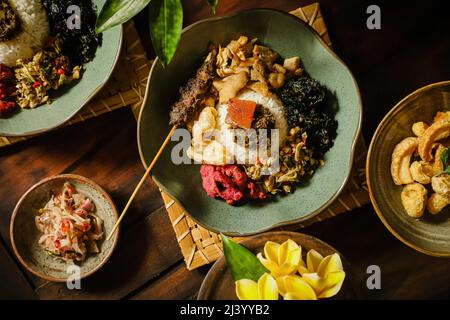 Nasi Campur Babi Guling. Balinesisches Gericht mit Reis und Schweinebraten, anderen Schweinefleisch- und Gemüsegerichten Stockfoto