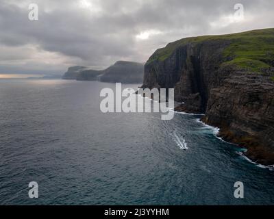 Wunderschöne filmische Luftaufnahme des Wasserfalls von Bøsdalafossur und des Sees von Trælanípan - Lagune herrliche Wahrzeichen auf den Färöer Inseln Stockfoto