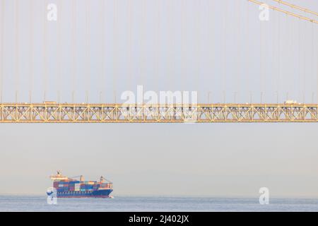Frachtschiff, das unter Brückenspannweite überquert Stockfoto