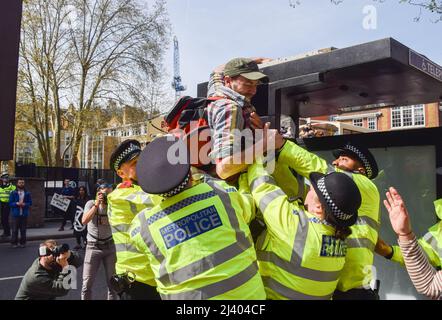 London, England, Großbritannien. 10. April 2022. Polizeibeamte verhindern, dass ein Protestler während des marsches im Zentrum von London auf eine Telefonzentrale klettert. Die Demonstranten der Extinction Rebellion setzen ihre jüngste tägliche Kampagne fort, die voraussichtlich mehr als eine Woche andauern wird, und fordern die Regierung auf, fossile Brennstoffe zu beenden und gegen den Klimawandel zu handeln. (Bild: © Vuk Valcic/ZUMA Press Wire) Stockfoto