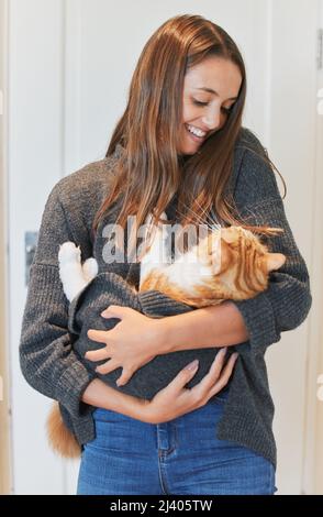 Ich möchte nur eine Stay-at-Home-Katze-Mutter sein. Aufnahme einer jungen Frau, die ihre Katze zu Hause trägt. Stockfoto