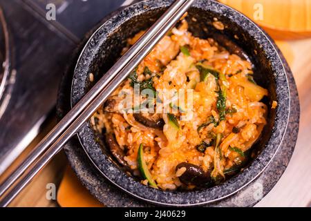 Bibimbap in einer schwarzen, beheizten Steinschüssel, koreanisches traditionelles Gericht - Bibimbap gemischter Reis mit Gemüse umfassen Rindfleisch und Spiegelei, japanisches Hot Pot Essen Stockfoto