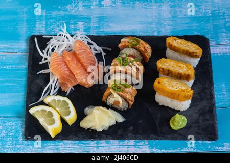 Verschiedene Sushi- und Sashimi-Platten. Lachs-Sushi-Brötchen, Lachs-Sashimi, Wasabi, Ingwer, Zitrone. Stockfoto