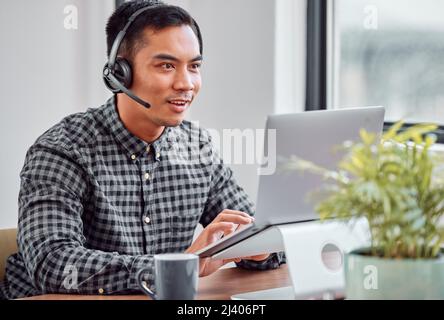 HES auf eine Lösung. Eine kurze Aufnahme eines hübschen jungen Agenten im Callcenter, der an seinem Laptop arbeitet. Stockfoto