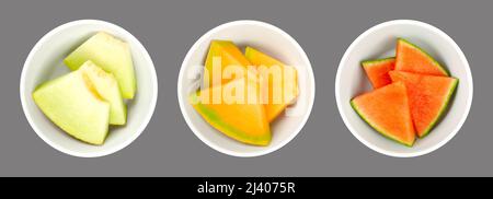 Melonenscheiben, in weißen Schalen, über grau. Galia, Honig Cantaloupe Melone und Wassermelone. Frisch geschnittene, dreieckige Stücke. Stockfoto