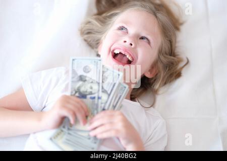 Kleines Mädchen ohne Vorderzähne, das Geld in den Händen hält und lächelt Stockfoto