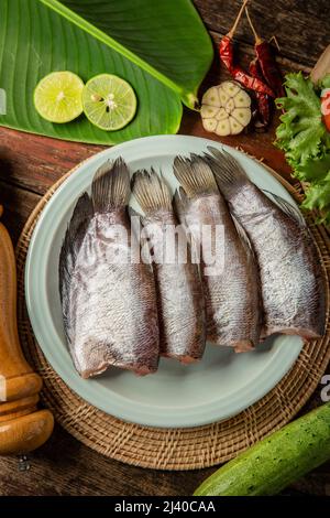 Frischer Fisch auf dem Tisch garniert mit Gemüse Stockfoto