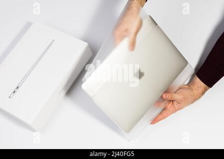 Saratov, Russland - 26. Februar 2022: Nehmen Sie silberne Macbook Air 13 Zoll mit M1 Prozessor aus Schutzpaket topview, weißer Hintergrund Stockfoto