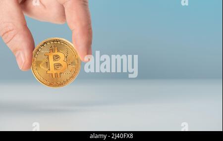 Mann Hand halten goldene Bitcoin. Bitcoins und neues Virtual Money-Konzept. Nahaufnahme des Geschäftsmannes, der Bitcoin in goldener Farbe hält und zeigt. Virtuelle c Stockfoto