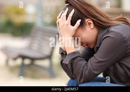 Seitenansicht Porträt einer verzweifelten Frau, die sich allein in einem Park beschwert Stockfoto