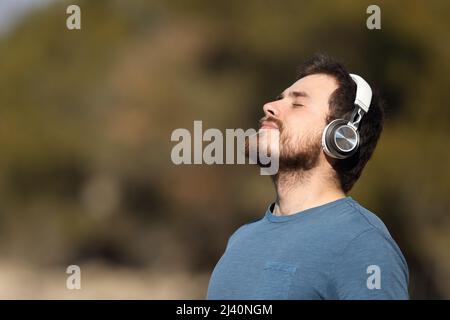 Profil eines Mannes, der mit kabellosen Kopfhörern in der Natur meditiert Stockfoto