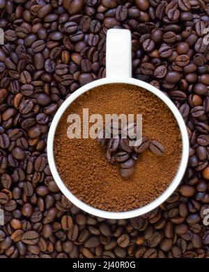 Kaffeebohnen auf dem Boden und frisch gerösteter Kaffee in der Tasse Stockfoto