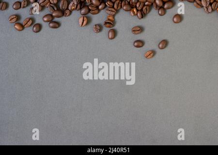 Top Gießen gerösteten Kaffeebohnen auf grauem Hintergrund. Kann als abstrakter Hintergrund verwendet werden. Stockfoto