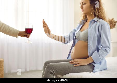 Der Schwangeren wurde ein Glas Wein angeboten, was eine Stop-Geste machte und sich weigerte zu trinken Stockfoto