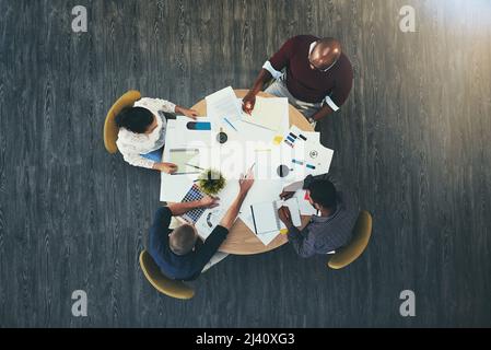 Reden wir über Profit. Aufnahme einer Gruppe von Geschäftsleuten, die in einem modernen Büro ein Meeting abhalten. Stockfoto