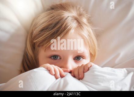 Ich fühle mich überhaupt nicht gut. Aufnahme eines kleinen Mädchens, das sich zu Hause im Bett krank fühlt und sich mit einer Decke bedeckt. Stockfoto