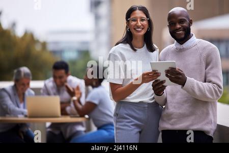 Denken Sie daran, Meilensteine zu feiern. Aufnahme von zwei professionellen Mitarbeitern, die bei der Arbeit zusammen ein digitales Tablet nutzen. Stockfoto