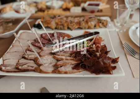 Schneiden verschiedener Fleischsorten. Fleischsnacks auf dem Tisch. Hochzeitsbuffet Stockfoto