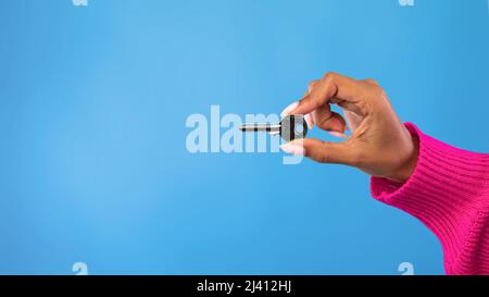 Beschnittene Ansicht einer jungen schwarzen Frau mit Metallhaustaste auf blauem Studiohintergrund, Panorama mit Kopierraum Stockfoto