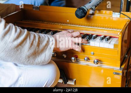28.. Februar 2010. Inis Rath, Fermanagh, Nordirland. Ein Hare-Krishna-Anhänger in einer verblassten Robe spielt während einer Tempelzeremonie eine Quetschbox Stockfoto
