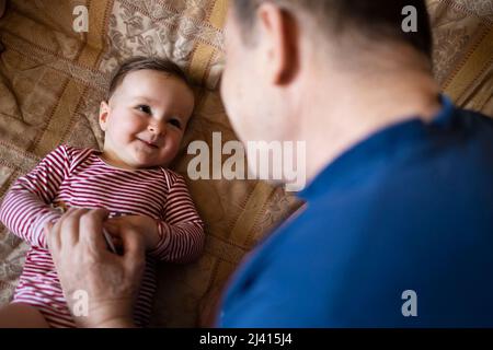 Enkelin lächelt und spielt mit ihrem Großvater Stockfoto