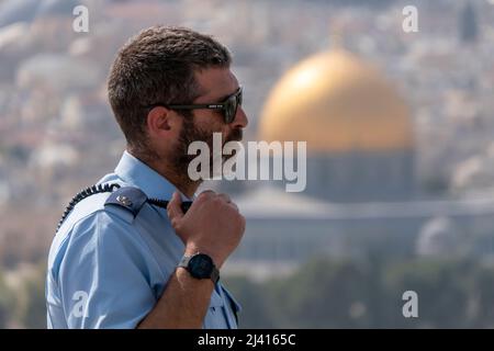 Ein israelischer Polizeibeamter steht auf dem Ölberg vor dem Hintergrund des vergoldeten Schreinkuppel des Felsens auf dem Tempelberg, der den Muslimen als Haram esh-Sharif in der Altstadt von Ostjerusalem Israel bekannt ist Stockfoto