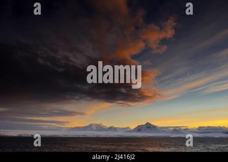 Am frühen Morgen fällt Licht auf die Berggipfel der Anvers Island vor der Küste von Danco, Antarktis. Bismarckstraße im Vordergrund Stockfoto