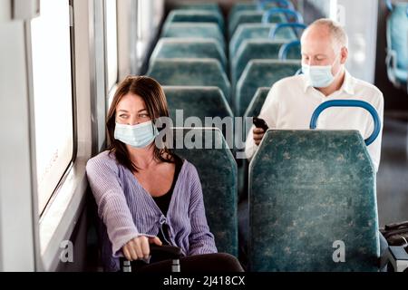 Ernsthafte Passagiere in Schutzmasken während ihrer Zugfahrt Stockfoto