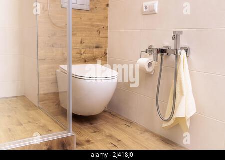 toilette und hygienische Dusche im Badezimmer mit Keramikfliesen in natürlichen Farben Stockfoto