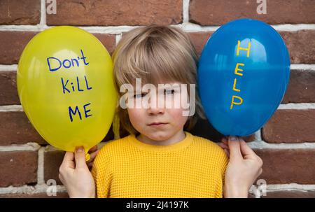 Kind mit blaugelben Luftballons, mit Inschriften, tötet mich nicht, helft. Angst, Verzweiflung, die Aufmerksamkeit auf den militärischen Konflikt in der Ukraine. Morde an Stockfoto