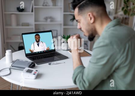 Telemedizinisches Konzept. Krank Arabischer Mann Mit Video Anruf Mit Lächelnd Schwarz Arzt Stockfoto