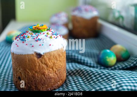 Osterkomposition mit traditionellem russischem Osterbrot kulich, Ostereiern und Fliederblumen auf dem Tisch. Stockfoto